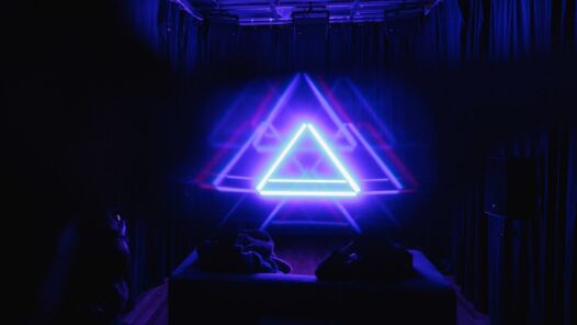 Picture of LED light strip immersive pyramid installation in a small room that's being diffracted and creating ghostly symmetrical triangular repetitions.