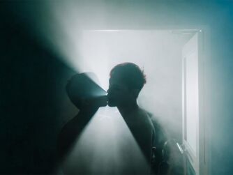 Two men kissing in a steam room back light with dramatic lighting